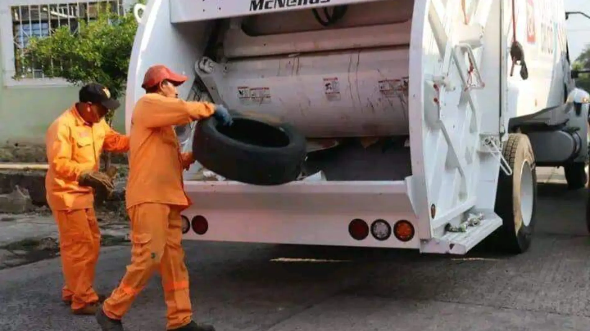 trabajadores de basura cargando llantas